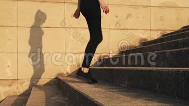 穿着黑色运动服跑上台阶的年轻女子。 女孩在逃跑。 天气晴朗，温暖。 一个年轻女孩跑了