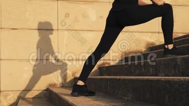 穿着黑色运动服的年轻女子在训练中弯曲大腿内侧的<strong>肌肉</strong>。女孩伸展<strong>腿部肌肉</strong>