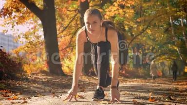 年轻的白种人女孩穿着连衣裙在起跑线上准备在秋季公园跑步