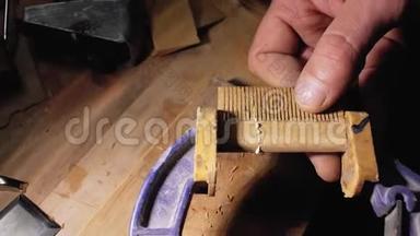 专业熟练的木匠用刮痕paper.craftsman.handmade打磨木胡须梳子.. 木匠师傅正在抓