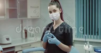 现代诊所的年轻护士助理，脸上戴着外科口罩，直视着摄像机，手里拿着一个