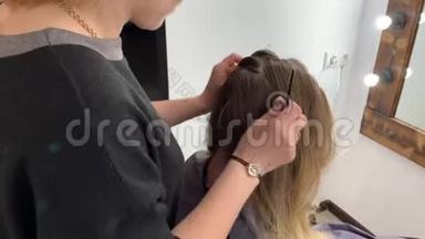 理发师编辫子的女人在美发沙龙`头发。