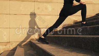 穿着黑色运动服的女人在训练中弯曲大腿内侧的<strong>肌肉</strong>。 女孩伸展<strong>腿部肌肉</strong>之前
