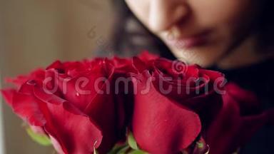 美丽的女孩嗅<strong>着</strong>一束红玫瑰，然后<strong>看着窗外</strong>。 特写