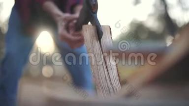一个穿格子衬衫和牛仔裤的人把木头切成两块。 福斯特切木头。