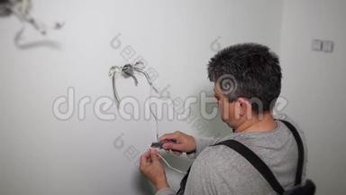 工人准备电线连接石膏墙孔中的插座花环框架