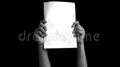 双手向上，显示黑色垂直白色纸张隔离在黑色背景，理想的广告用途使用