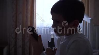 <strong>儿童保健</strong>，生病的小男孩使用手机，同时通过雾化器治疗气道炎症。
