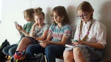 青少年和智能手机。 孩子们在<strong>放学</strong>时使用智能手机。 一群学童坐在长凳上