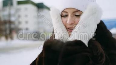 一个穿着<strong>貂皮</strong>大衣的漂亮女孩用针织毛皮手套温暖她的脸颊。