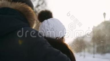 男孩拥抱女孩。<strong>飞舞</strong>的<strong>雪花</strong>在阳光下闪闪发光。冬天散步。