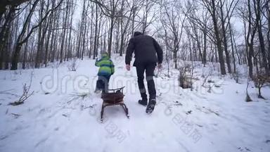 父母支持，<strong>父亲帮助</strong>儿子在冬天用雪橇爬雪山