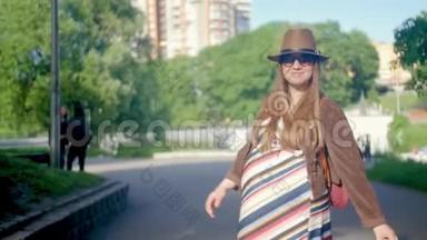 年轻的孕妇散步，四处走动，享受她的闲暇时间在公园一个夏天。 带图案的浅色长裙