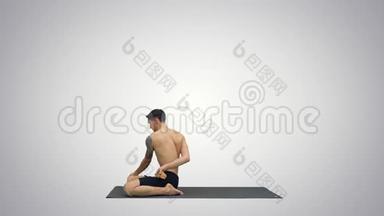 一个做<strong>瑜伽</strong>练习的年轻壮汉在渐变背景下伸展帕德马萨纳腿。