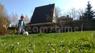 一个快乐的孩子快乐地踢足球，跑过一片绿草地