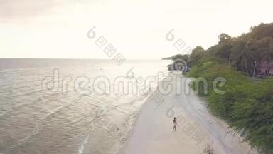 鸟瞰海岸线和海浪在海滩上行走的年轻女孩在热带背景。 一段<strong>穿越时空</strong>的镜头