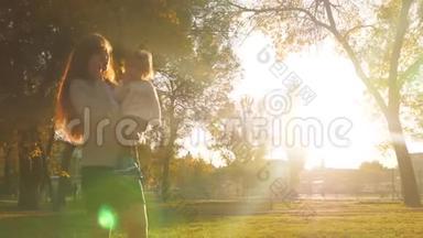 <strong>母亲抱</strong>着<strong>孩子</strong>，用手机说话。 一家人晚上在城市公园散步。
