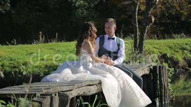 新娘坐在<strong>河边</strong>的一座木桥上。 一对幸福的家庭夫妇，花时间在<strong>公园</strong>里