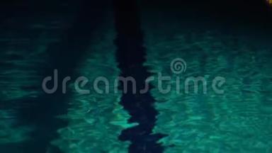 在夜间的游泳池里，在深水处掀起波浪。