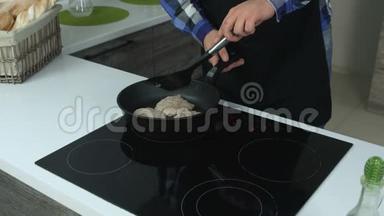 一个穿着围裙的胖子用电饭锅上的薯条切块，用铲子把它们压起来。 一个穿围裙的男人