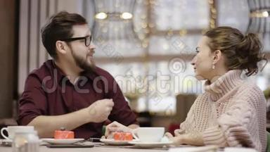一对漂亮的夫妇坐在一桌一桌的餐馆里，当服务员拿着一盒装满鲜花的盒子，男人把它送给他的时候