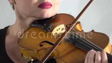女孩拿着小提琴在琴弦上鞠躬。 快关门。 白色背景