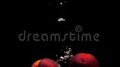 两个成熟的桃子在黑色的背景下落入透明的水中