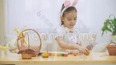 头上<strong>戴</strong>着兔子耳朵的小女孩正在木桌上玩耍，满是复活节的装<strong>饰品</strong>。 女孩是