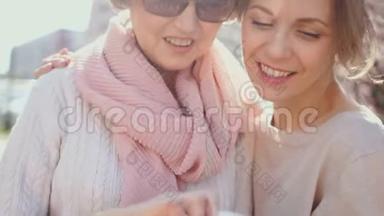 两个女人在智能手机里讨论照片。公园里的春画像。网络营销、传销业务