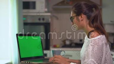 年轻的黑发女人在笔记本电脑上工作，<strong>在家</strong>里<strong>上网</strong>学习绿色屏幕色度键