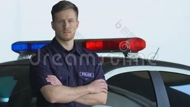 英俊的警察站在警车旁边看着摄像机，<strong>值班</strong>