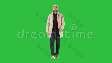 深色胡须的人穿着浅色的风衣走在绿色的屏幕上，Chroma键。