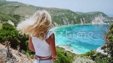 快乐和幸福的概念，年轻的金发女人摇动她的头发，头发在风中飞扬。 她享受着奇妙的海景
