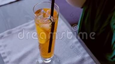 女人把酒精鸡尾酒和吸管混合在香槟笛子上，用橙色喝，双手特写。