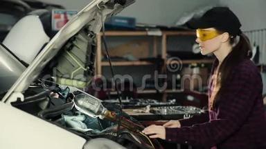 漂亮的女机械师，深色头发，穿着格子衬衫和帽子，戴着防护眼镜修理汽车发动机。 概念