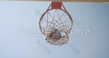 从下往上看，篮球球被扔到室外的篮筐里，天空在球场上