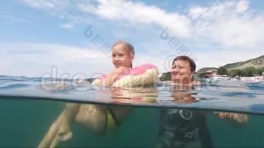 祖母带着一个小可爱的孙女在海里洗澡，家庭幸福。 祖母教的小东西