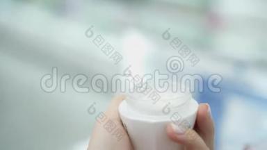 女人手打开奶油。 涂抹护肤霜