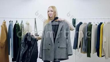有魅力的年轻女子在更衣室里展示一件外套和一件皮夹克