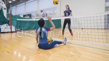 <strong>残疾人运动</strong>。 体育文化。 一位年轻女子坐在体育馆的地板上和她一起打排球