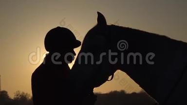 马女在日落时<strong>亲吻</strong>一匹马。 <strong>剪影</strong>。 慢动作。 侧视。 关门