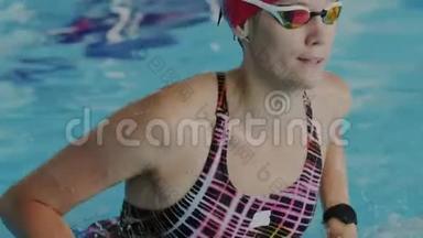 年轻的女运动员从游泳池的<strong>水里出来</strong>。她恢复了呼吸，摘下护目镜，看着