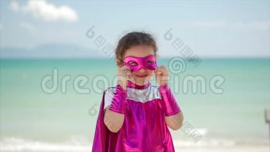 穿着超级英雄服装的漂亮小女孩，穿着粉红色的斗篷和英雄的面具。 坐在飞机上