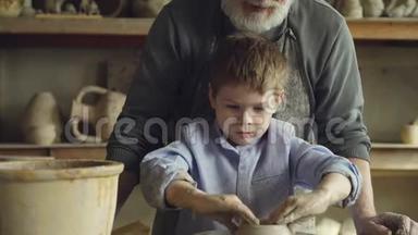 当他的老师有经验的雕塑家是一个集中的小男孩在投掷轮上制作粘土图形的倾斜镜头