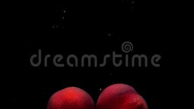 两个成熟的桃子在黑色的背景下落入透明的水中