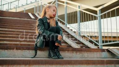 穿黑色<strong>皮夹克</strong>的摇滚女孩坐在楼梯上。 穿黑色<strong>皮夹克</strong>的年轻女孩坐在楼梯上