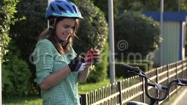 年轻的白种人女学生用手拿手机触摸<strong>屏幕</strong>。 一个女人站在阳光明媚的出租<strong>城市</strong>自行车附近