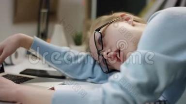 年轻漂亮的学生用笔记本电脑睡在桌子上