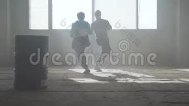 训练熟练的街舞者。 两个成功舞者的朋友正在一座废弃的尘土飞扬的建筑里跳舞