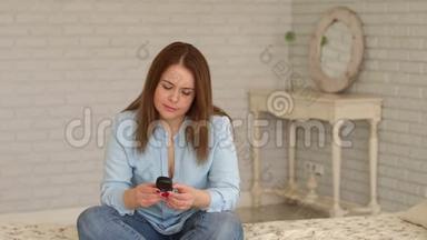 一位患有糖尿病的妇女坐在家里的床上，手里拿着<strong>血糖仪</strong>